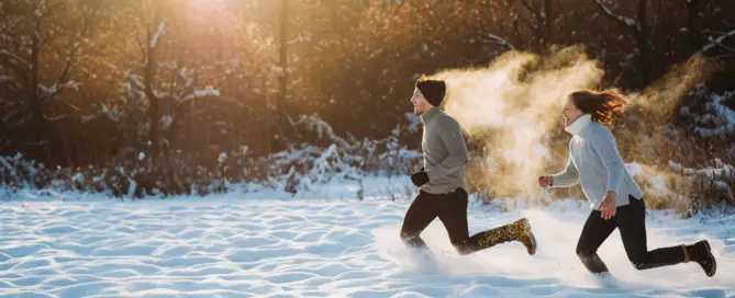 Zwei Menschen rennen lachend durch verschneite Landschaft im Winter – Symbol für starke Abwehrkraft, Energie und Lebensfreude mit TCM
